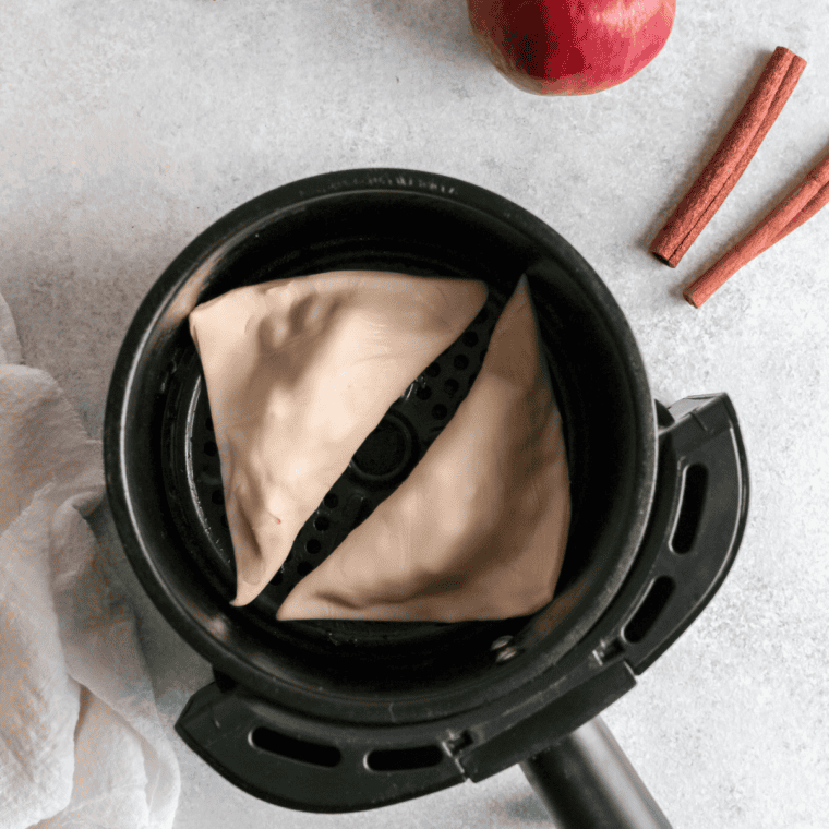 Golden-brown turnovers baking on a parchment-lined tray inside the oven, or air fryer.