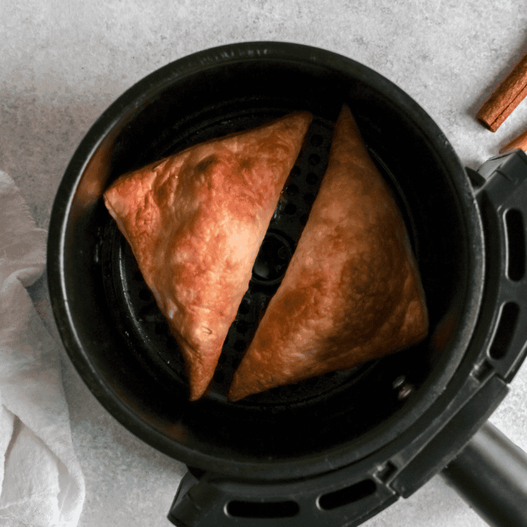 Small bowl of powdered sugar and milk being mixed to form a smooth glaze.
Freshly baked turnovers being drizzled with a glossy glaze from a spoon.