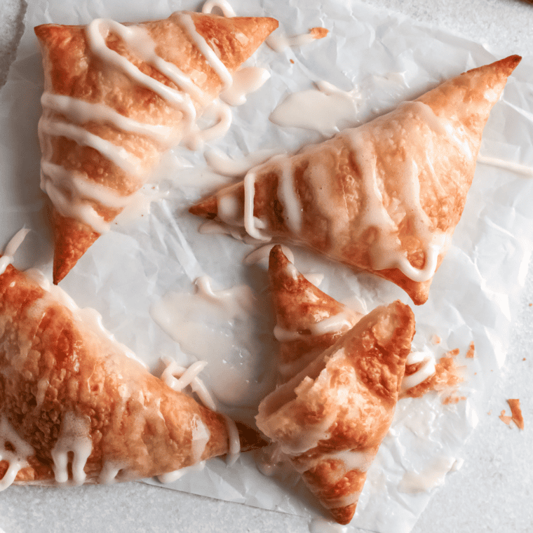 Golden, flaky Hardee’s-style apple turnovers with a sweet apple filling, dusted with powdered sugar on a plate