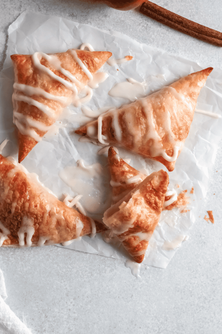 Golden, flaky Hardee’s-style apple turnovers filled with spiced apple filling and drizzled with a sweet glaze, served on a plate.