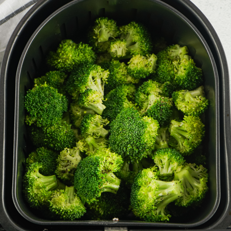 Broccoli florets steaming in a pot with a steamer basket, vibrant green and tender.