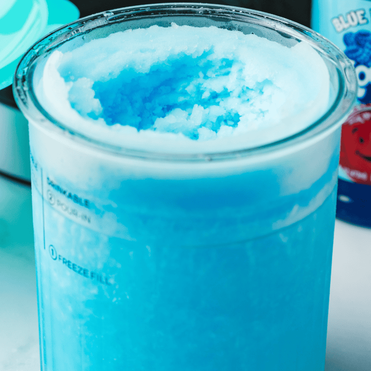 Pouring the blue raspberry mixture into a Ninja Creami pint container, securing the lid, and placing it in the freezer.