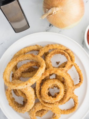 "A towering stack of crispy, golden-brown onion rings served on a plate with dipping sauces."