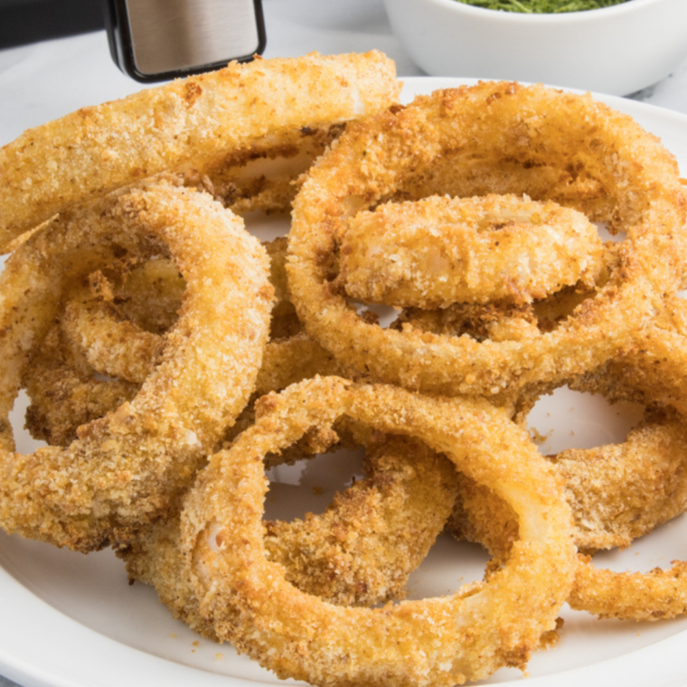 Plate of golden, crispy Red Robin Towering Onion Rings stacked high with dipping sauces on the side.