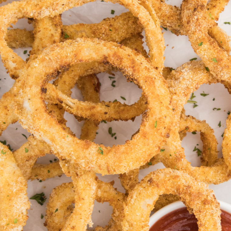 Golden, crispy Red Robin Towering Onion Rings stacked high on a plate with dipping sauces on the side.