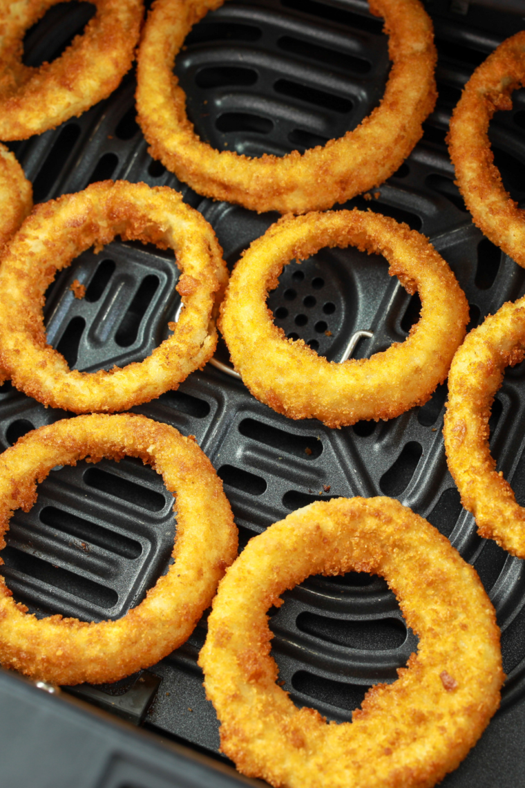 Golden, crispy Red Robin Towering Onion Rings stacked high on a plate with dipping sauces on the side.