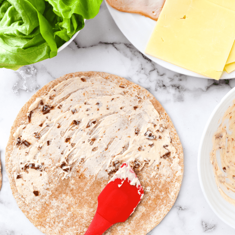 Tasting and adjusting the seasoning of sun-dried tomato spread, then refrigerating for enhanced flavor before serving on crackers, bread, or as a dip for veggies.