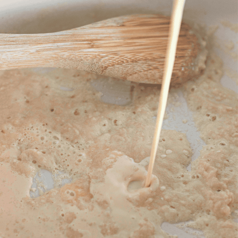 Melting butter in a saucepan and adding flour to create a roux for a creamy cheese sauce.