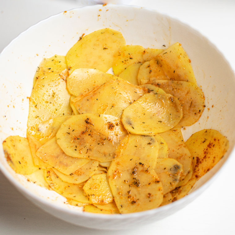 Thinly sliced potatoes prepared with a mandolin slicer, patted dry with paper towels for crispy air fryer chips.