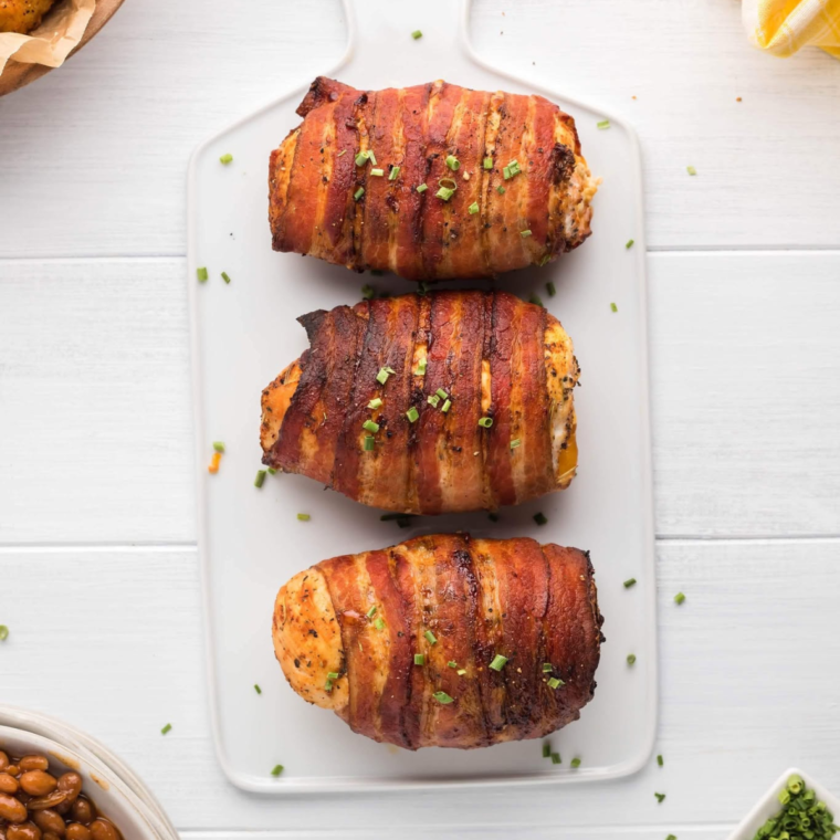 Crispy, golden-brown Air Fryer Bacon Wrapped Chicken Breast garnished with herbs.