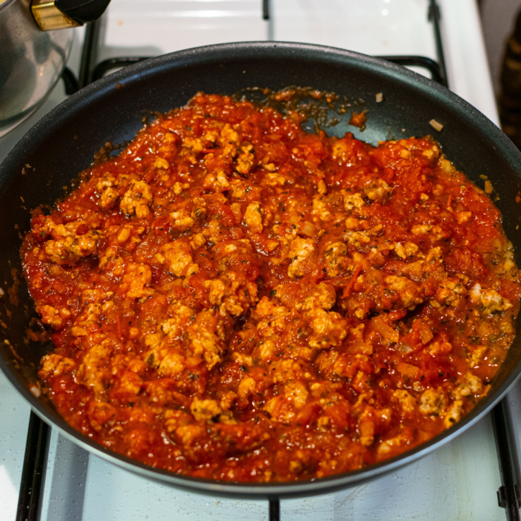 Step-by-step preparation of spaghetti with olive oil, browned ground beef, sautéed onion and garlic, marinara sauce, and seasonings in a skillet.