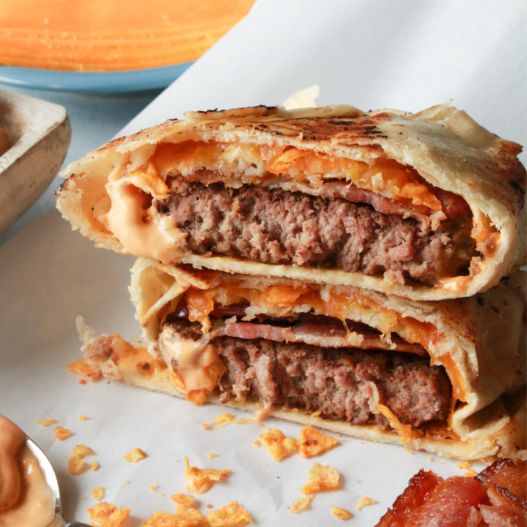 Golden Air Fryer Burger Crunch Wrap filled with juicy beef, melted cheese, crisp lettuce, fresh tomatoes, and savory sauce, served on a wooden board.