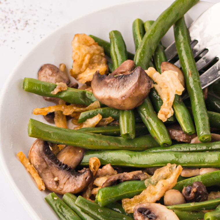 A plate of Air Fryer Green Beans with Mushrooms and Onions, garnished with crispy fried onions.