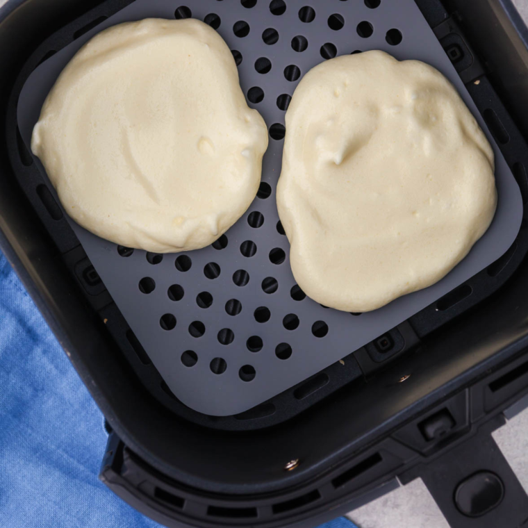 Place parchment paper or silicone mat in air fryer basket, then scoop cloud bread mixture into rounds and air fry at 300°F for 10-12 minutes, until golden and crispy.