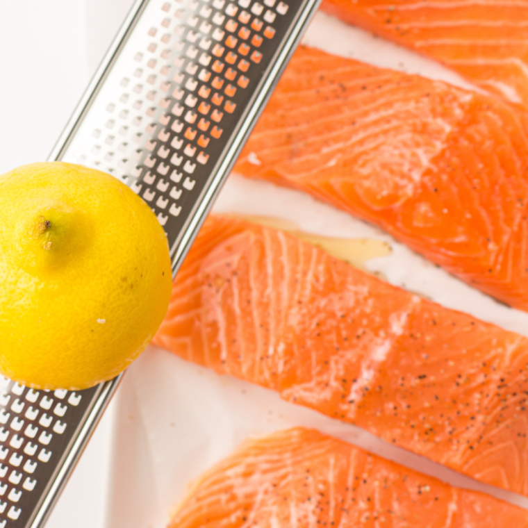 Salmon fillets seasoned with olive oil, garlic powder, salt, pepper, and lemon juice, ready to absorb the flavors.