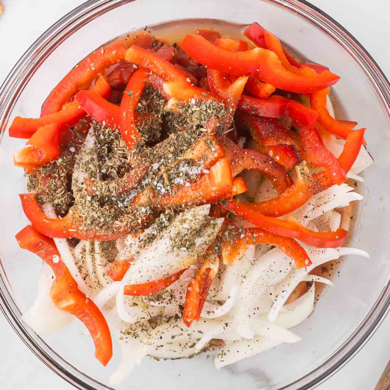 Ingredients for Air Fryer Salmon Cacciatore: bell peppers, onion, tomatoes, garlic, Italian seasoning, olive oil, salt, and pepper mixed in a bowl.