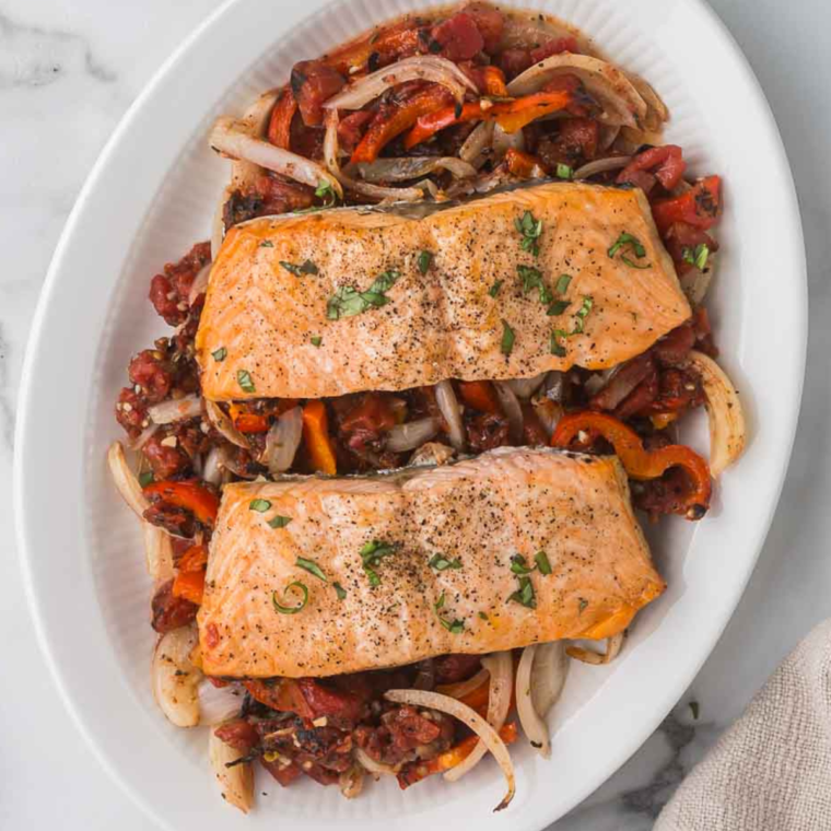 A plate of Air Fryer Salmon Cacciatore with vibrant bell peppers, tomatoes, and garnished with fresh basil.