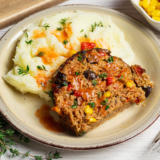 Air Fryer Southwest Meatloaf sliced and served with a side of fresh vegetables on a plate.