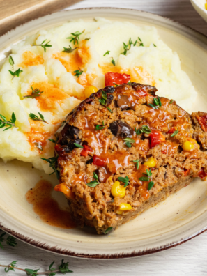 Air Fryer Southwest Meatloaf sliced and served with a side of fresh vegetables on a plate.