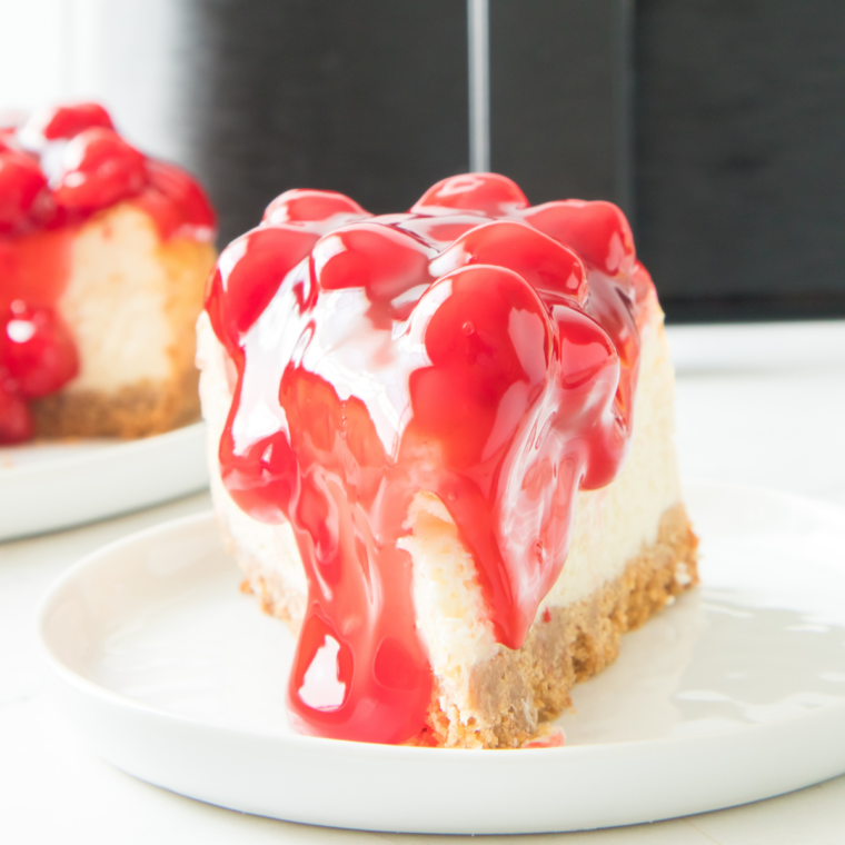 Creamy Air Fryer Cherry Cheesecake topped with glossy cherry filling and served on a white plate.