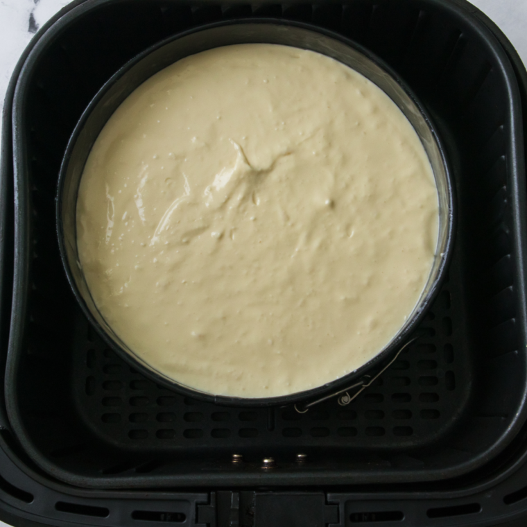 Placing the springform pan in the air fryer basket and cooking at 320°F (160°C) for 20-25 minutes until the cheesecake is set.