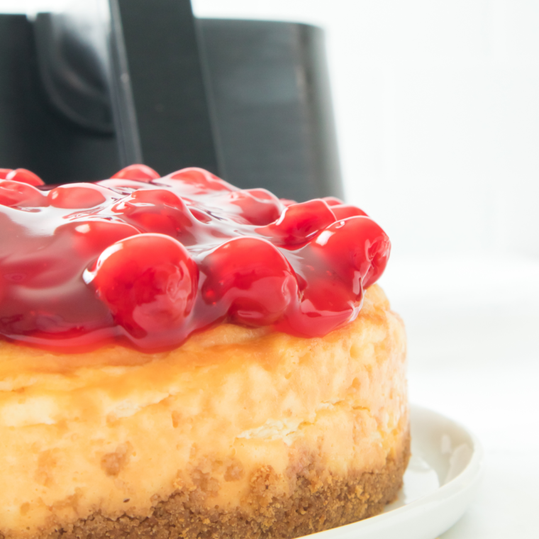 Air Fryer Cherry Cheesecake topped with a glossy cherry filling, served on a white plate.