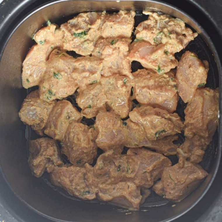 Marinating chicken pieces with yogurt, garlic, ginger, and spices for Chicken Tikka Salad.