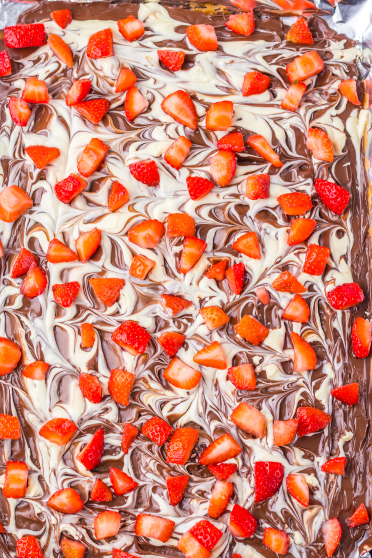 A close-up of Chocolate Covered Strawberry Bark with melted chocolate and fresh strawberry pieces.