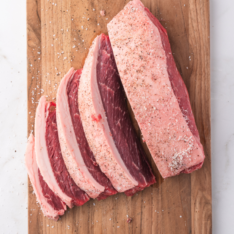 Cutting picanha into 2-inch slices and shaping them into a C curve, ready to be threaded onto metal skewers.