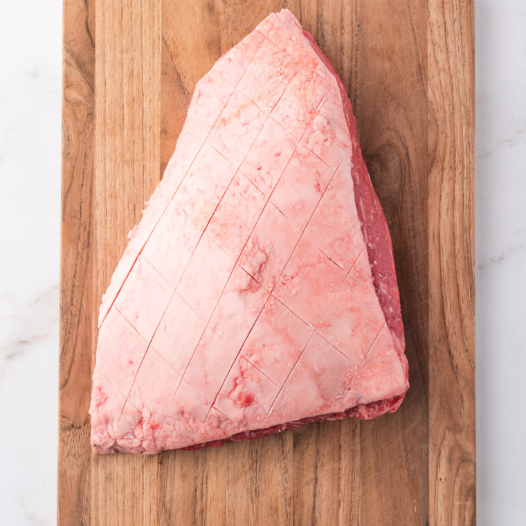 Scoring the fat cap of picanha in a crisscross pattern and seasoning with coarse salt and black pepper.