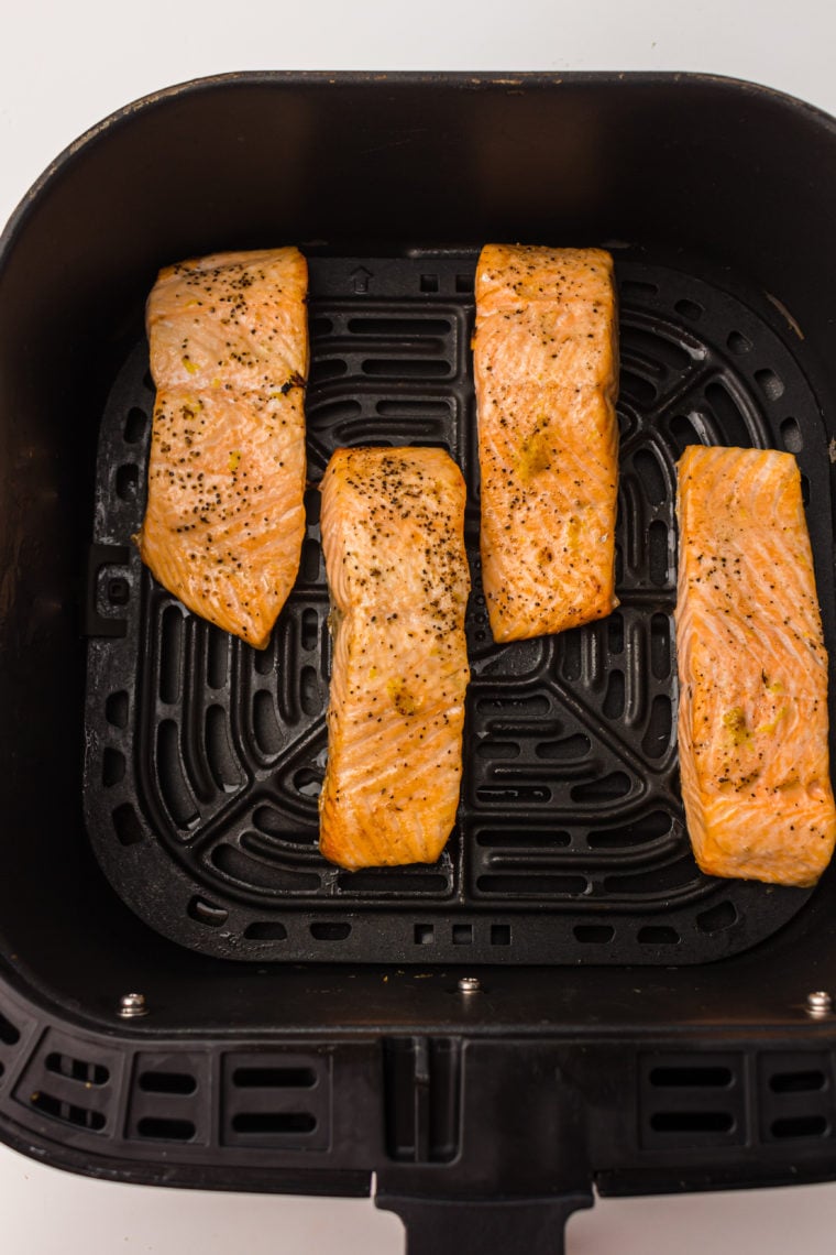 Cooked salmon fillets in the air fryer basket, perfectly crispy on the outside and tender on the inside.