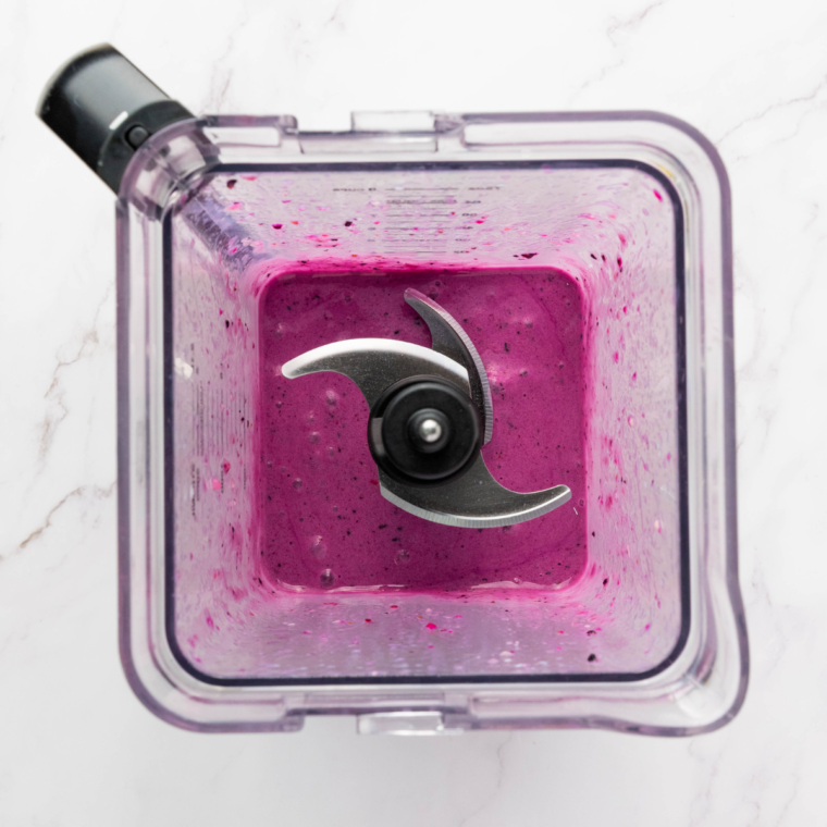 Filling a CREAMi™ pint with blended dragonfruit smoothie mixture, ready to freeze.