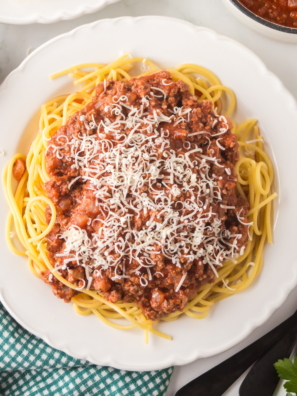 A hearty plate of Ninja Foodi Spaghetti Bolognese featuring tender spaghetti smothered in rich, savory Bolognese sauce, garnished with fresh parsley and grated Parmesan cheese.