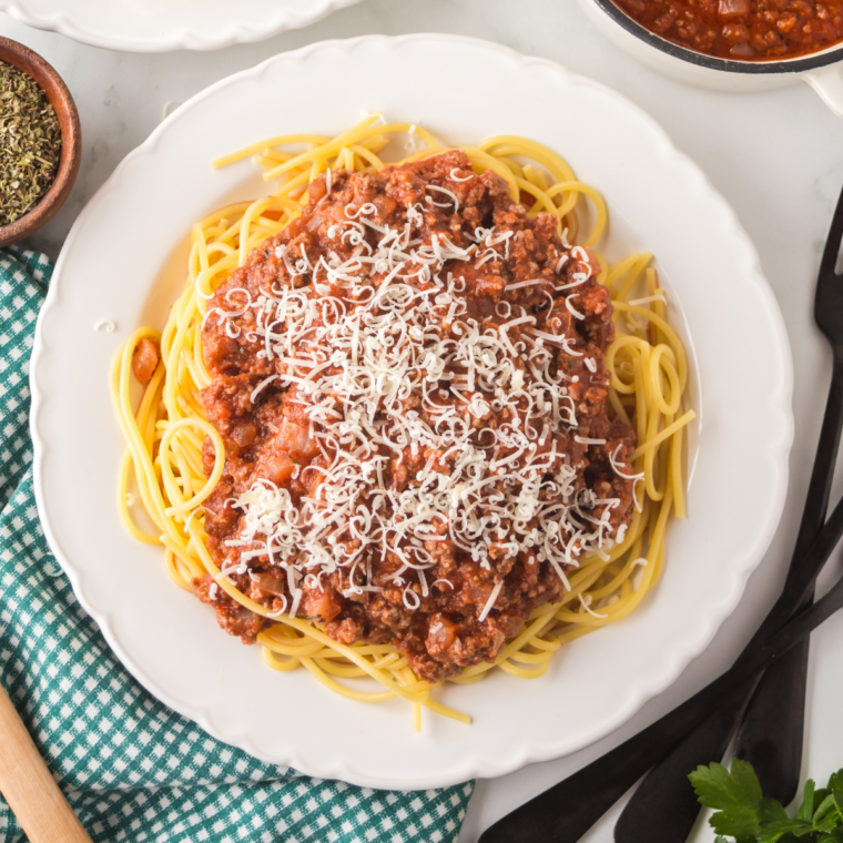 A hearty plate of Ninja Foodi Spaghetti Bolognese featuring tender spaghetti smothered in rich, savory Bolognese sauce, garnished with fresh parsley and grated Parmesan cheese.