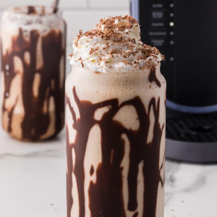 A glass of Ninja Slushi Caramel Frappuccino topped with whipped cream and caramel drizzle, ready to enjoy.