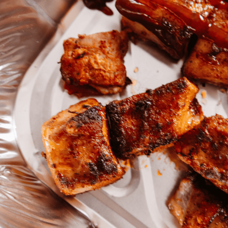 Transfer seared pork belly to aluminum pan, top with butter, brown sugar, and barbecue sauce, and cover with foil.