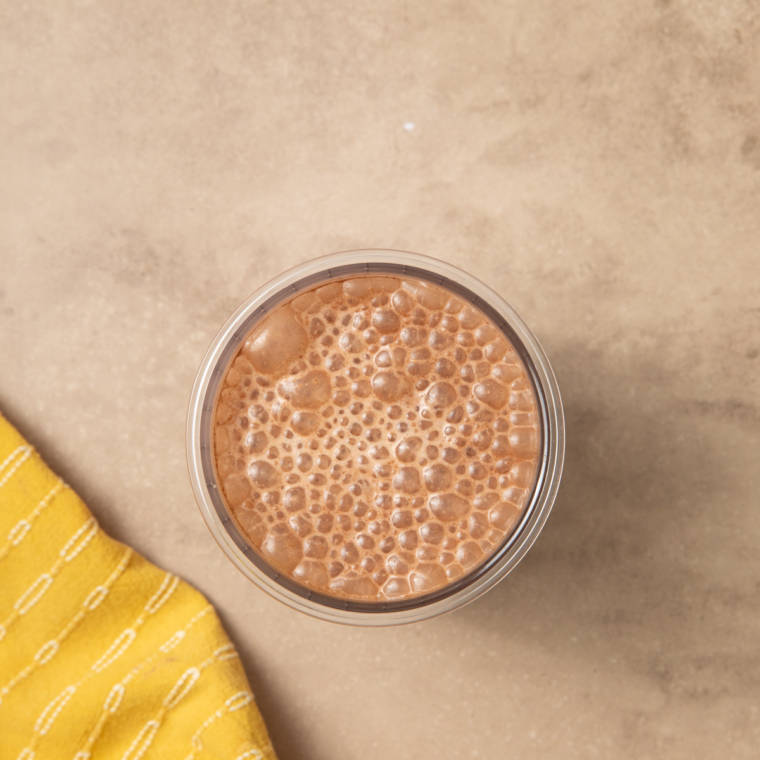 Mixing milk and protein powder in a Ninja® CREAMi® jar before freezing overnight.