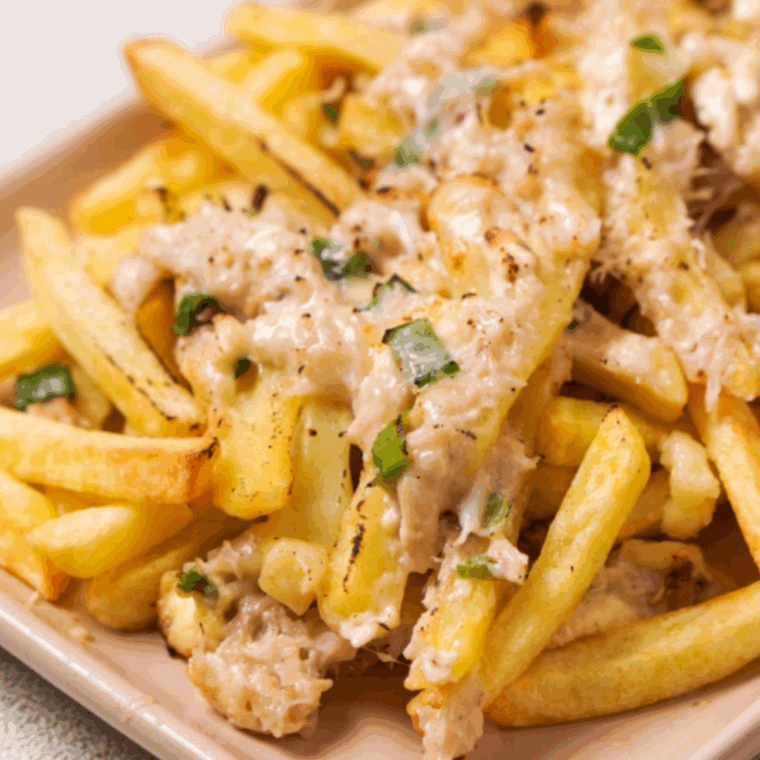 Plate of crispy fries topped with creamy crab cheese sauce and melted cheddar cheese.