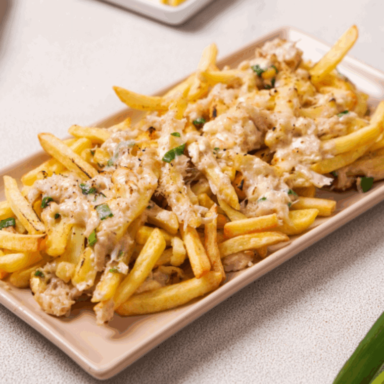 Close-up of golden fries smothered in melted cheese and crab meat, garnished with chopped green onions, inspired by Red Lobster’s Crabby Cheese Fries recipe.