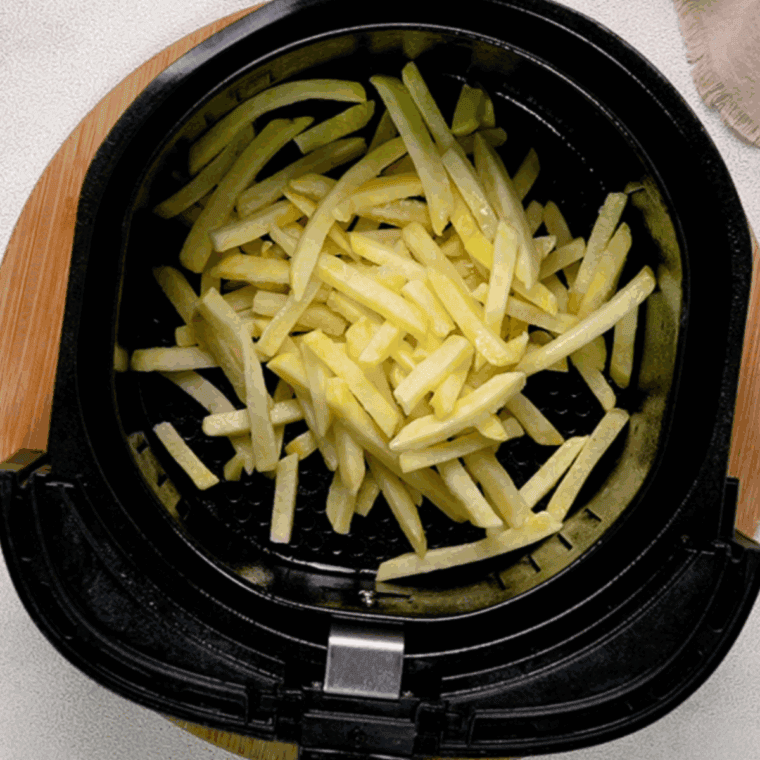 Golden and crispy French fries arranged in an air fryer basket, cooked to perfection at 400°F, ready for a delicious topping.