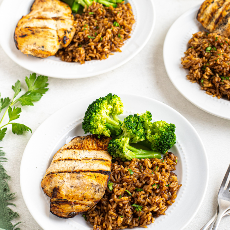 A bowl of Copycat Texas Roadhouse Seasoned Rice garnished with parsley, featuring buttery, flavorful rice cooked to perfection.