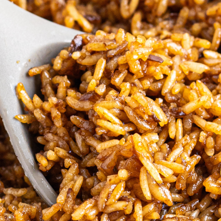 A bowl of Copycat Texas Roadhouse Seasoned Rice, perfectly spiced and garnished with fresh parsley, served as a savory side dish.