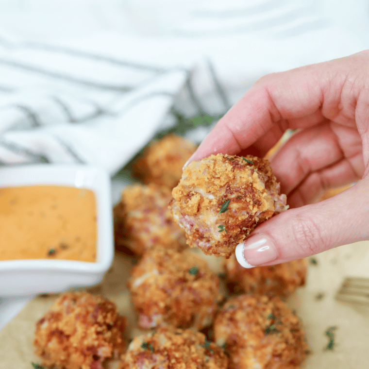 Golden Air Fryer Reuben Fritters filled with corned beef, Swiss cheese, and sauerkraut, served with Thousand Island dressing.