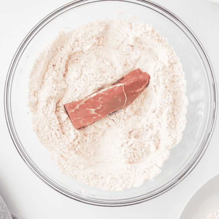 Mixing flour, salt, black pepper, garlic powder, and paprika in a shallow dish.