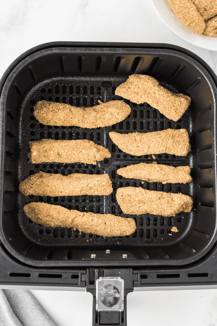 Lightly spraying air fryer basket with cooking spray, arranging breaded steak fingers in a single layer, and air frying at 400°F for 8-10 minutes until golden brown.