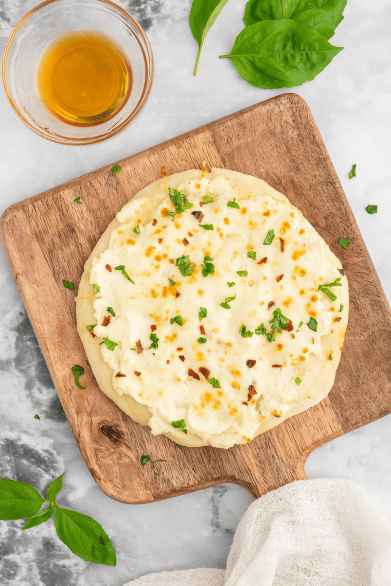 Air Fryer White Pizza (Pizza Bianca) with a golden crust, melted cheese, and fresh basil garnish on a wooden board.