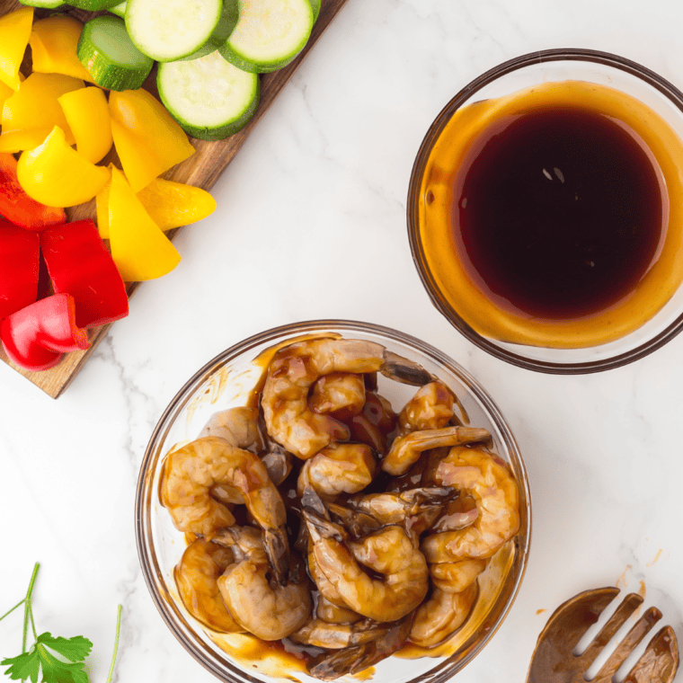 Shrimp coated with teriyaki sauce, marinating in a bowl.