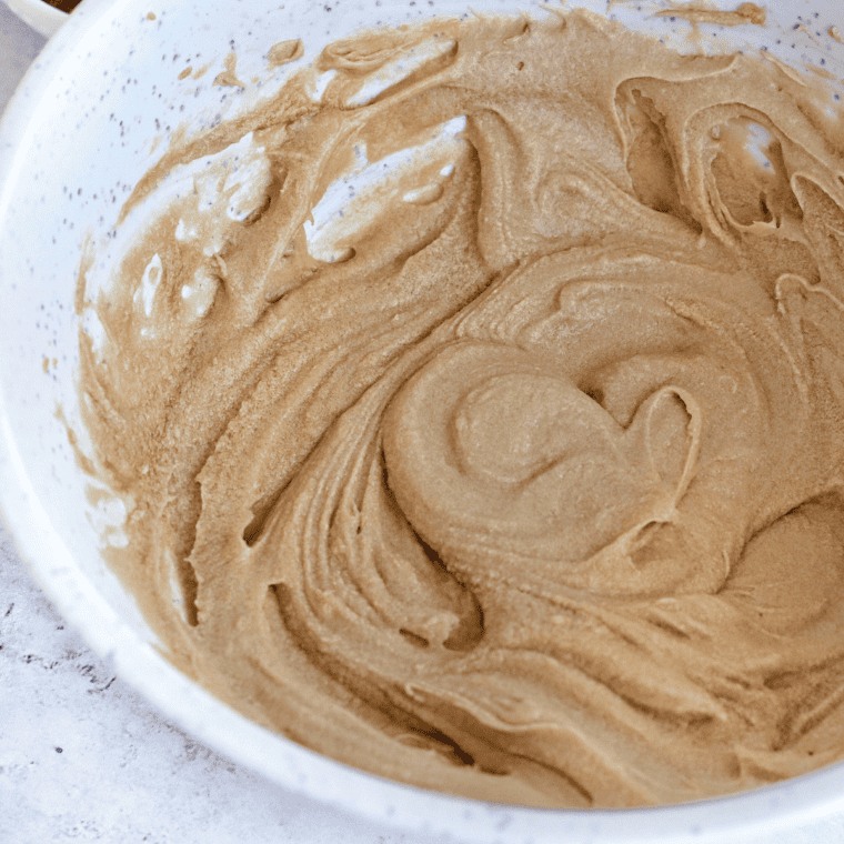 Mixing brown butter, peanut butter, sugars, and vanilla extract in a bowl with a hand mixer.