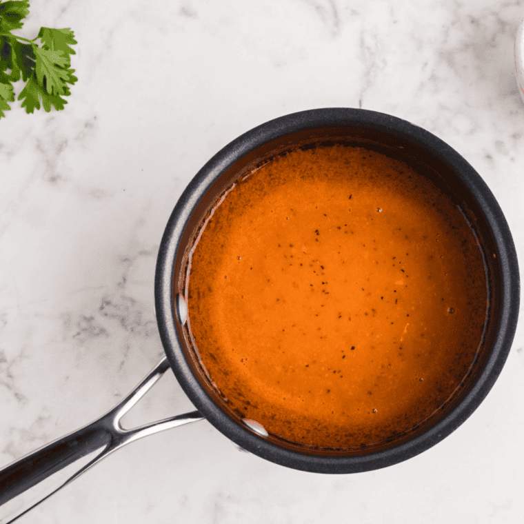 Whisking together ranch dressing and buffalo sauce with garlic powder, onion powder, dill, salt, and pepper in a mixing bowl.