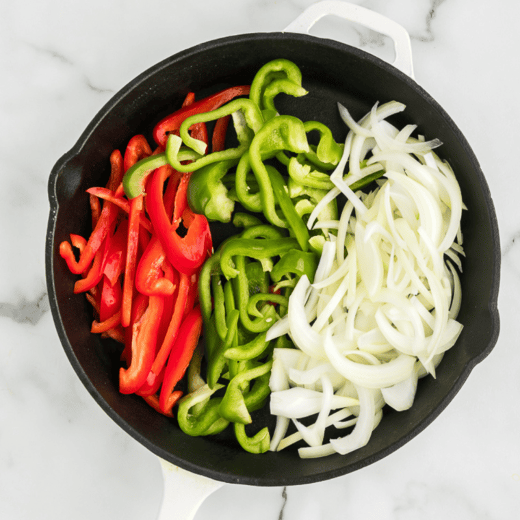 Slice bell peppers and onions into thin strips, heat olive oil in a skillet, and sauté onions until softened.